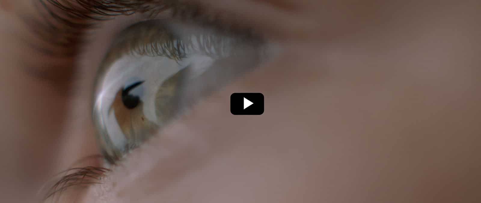 Close-up of a human eye with a play button overlay, indicating a video to play