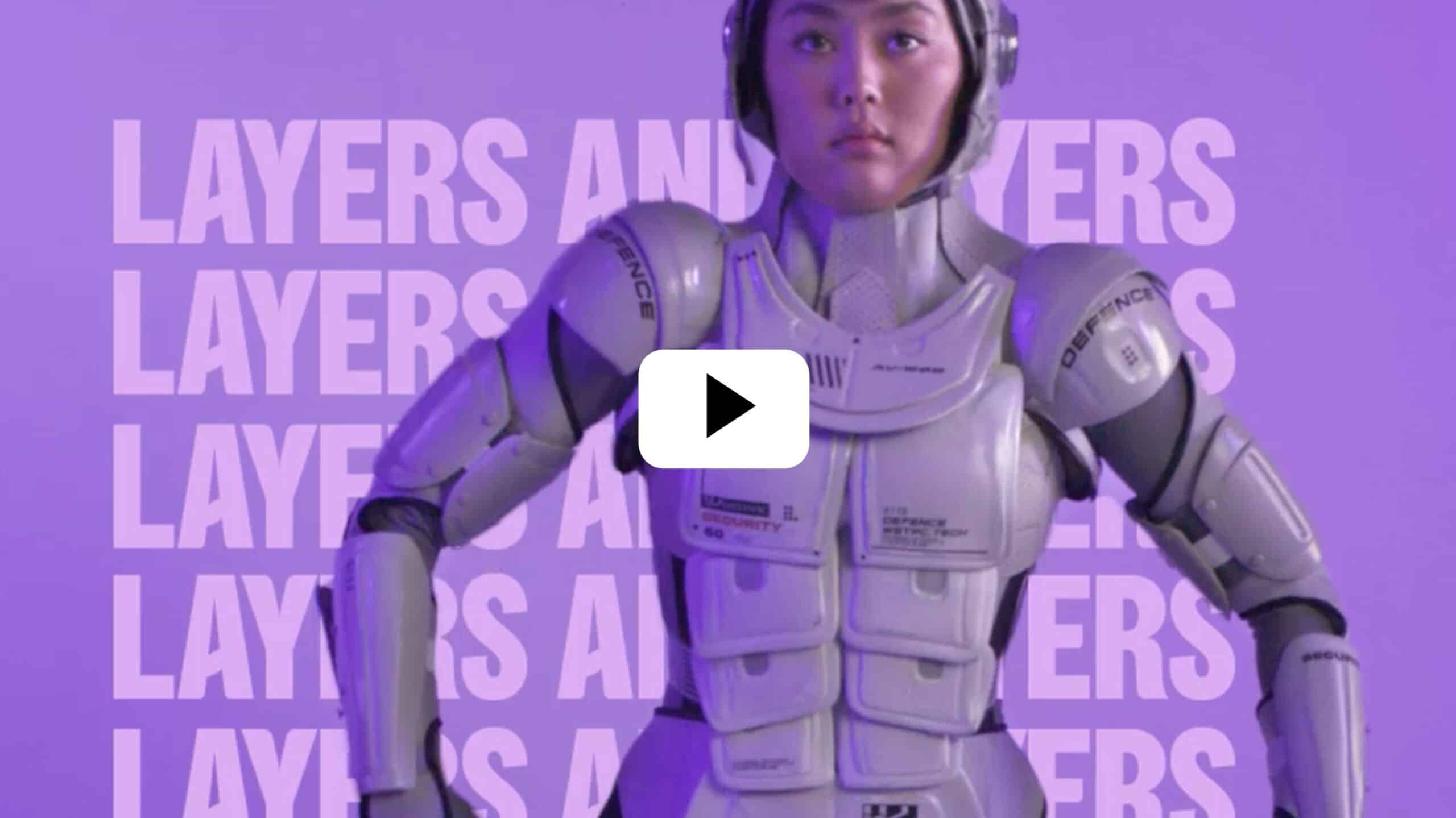 Video thumbnail of a person in a white futuristic armor suit against a purple background with the word 'LAYERS' repeated; centered play button overlays the image.